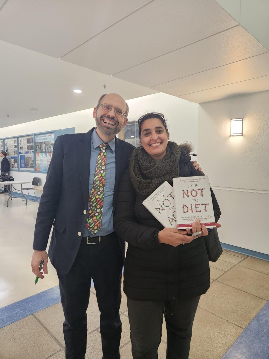 image of Tahani Elberjo and Dr. Michael Greger with copies of the book How Not To Die